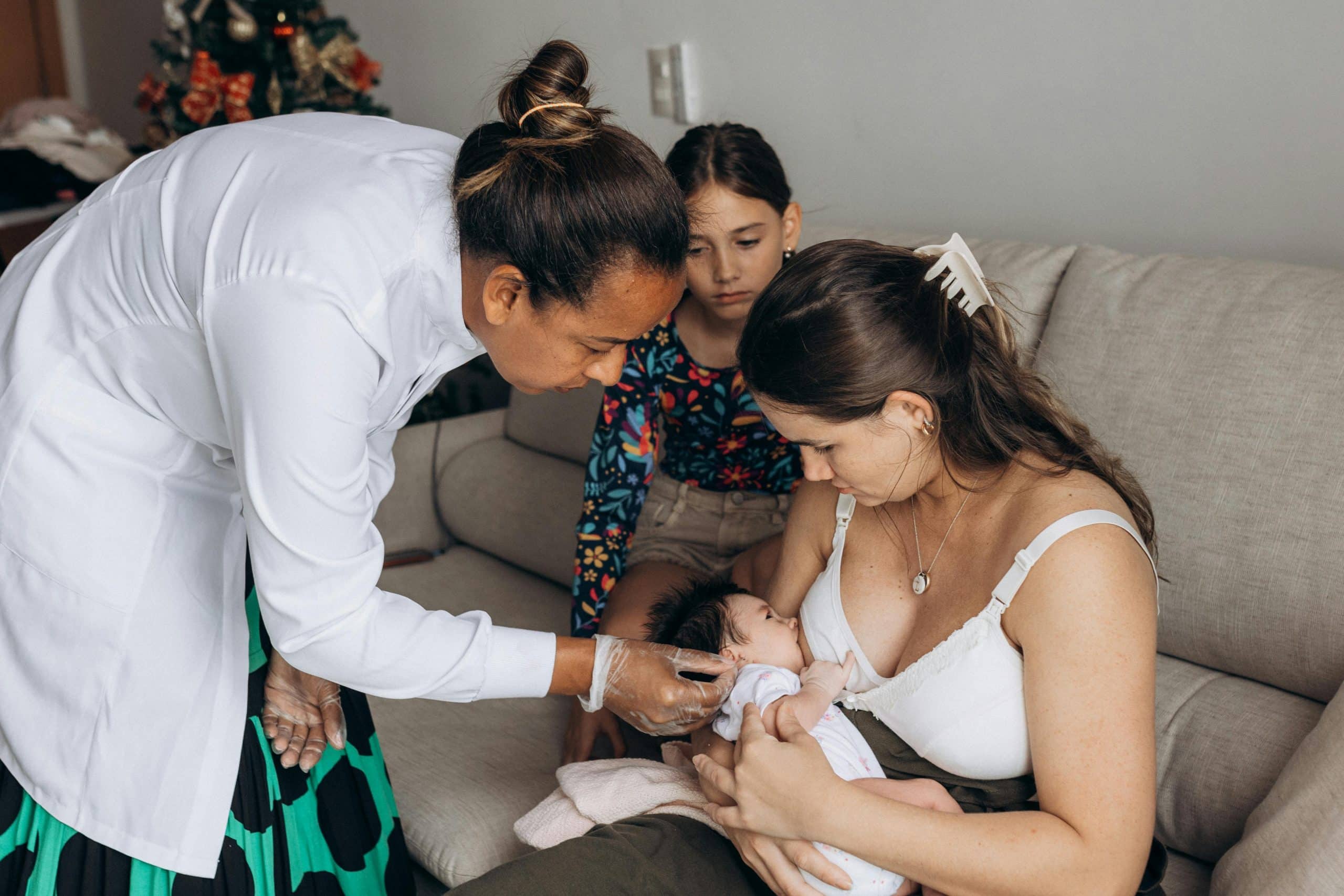 Mother breastfeeding medical professional assessing the feed